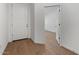 Open white foyer leading to a hallway with a white interior door and wood floors at 7421 S 76Th Ln, Laveen, AZ 85339