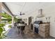 An outdoor kitchen features a stone-clad grill and stainless steel hood, dining table, and ceiling fan at 7835 E Cannon Dr, Scottsdale, AZ 85258