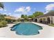 A beautiful in-ground pool with lounge chairs and umbrellas is surrounded by a white concrete patio and greenery at 7835 E Cannon Dr, Scottsdale, AZ 85258