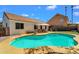 This backyard pool area has desert landscaping, an umbrella-covered outdoor table, and artificial grass at 823 W Kyle Ct, Gilbert, AZ 85233