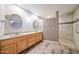 Bathroom featuring double sinks, wood cabinets, and a tiled walk-in shower at 8303 E Monterey Ave, Mesa, AZ 85209