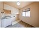 Functional laundry room featuring cabinets, a utility sink, a window, and wood flooring at 8303 E Monterey Ave, Mesa, AZ 85209