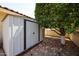 Metal storage shed situated near a tree with a gravel-covered ground at 8303 E Monterey Ave, Mesa, AZ 85209