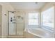 Modern bathroom showcasing a glass-enclosed shower and a soaking tub next to a window for natural light at 9412 S Palm Dr, Tempe, AZ 85284