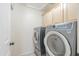 Laundry room with gray front-loading washer and dryer and light wood cabinets at 9412 S Palm Dr, Tempe, AZ 85284