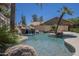 Backyard pool with a rock waterfall feature, palm trees, and desert landscaping at 9412 S Palm Dr, Tempe, AZ 85284