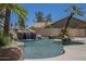 Outdoor swimming pool area with a rock waterfall and a palm tree island at 9412 S Palm Dr, Tempe, AZ 85284
