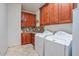 Well-equipped laundry room featuring tiled backsplash, wood cabinets, tile flooring, washer, and dryer at 1145 E Winchester Pl, Chandler, AZ 85286