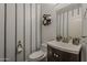 Powder room with decorative striped wallpaper and a unique toilet paper holder at 1441 E Folley Pl, Chandler, AZ 85225