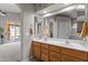 Bright bathroom with double sinks, wood cabinets, and a view to the backyard through the sliding door at 18066 W Weatherby Dr, Surprise, AZ 85374
