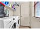 A convenient laundry room includes a washer, dryer, and shelving for storage at 21050 E Munoz St, Queen Creek, AZ 85142
