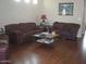 Cozy living room featuring wood floors, two leather sofas, and a glass coffee table at 21050 E Munoz St, Queen Creek, AZ 85142