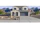Inviting two-story home featuring a gray garage door, desert landscaping, and mountain views at 24237 W Southgate Ave, Buckeye, AZ 85326