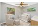 Cozy Bedroom featuring a crib, rocking chair, and two bright windows at 2913 E Earll Dr, Phoenix, AZ 85016
