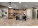 Open kitchen with central island, custom cabinets, travertine floors, stainless appliances, and a double beverage cooler at 3531 E Norwood Cir, Mesa, AZ 85213