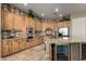 Well-lit kitchen featuring travertine flooring, custom cabinetry, granite countertops, stainless appliances, and beverage cooler at 3531 E Norwood Cir, Mesa, AZ 85213