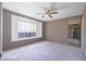 Bright bedroom featuring a large window seat, neutral carpeting, ceiling fan and a large mirror at 3823 W Rose Ln, Phoenix, AZ 85019