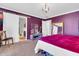 Bedroom with barn door access to bath, featuring unique chandelier and vibrant purple accent wall at 40638 N High Meadows Dr, San Tan Valley, AZ 85140
