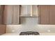 A close up on modern kitchen, highlighting the tiled backsplash, stainless steel exhaust fan, and gas range at 4227 W Adobe Dr, Eloy, AZ 85131