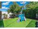 A well-maintained backyard with artificial grass, a playground, and mature trees at 4842 E Fairmount Ave, Phoenix, AZ 85018