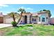 Charming single-story home with tile roof, arched entryway, and lush green lawn with well maintained landscaping at 705 W Country Estates Ave, Gilbert, AZ 85233