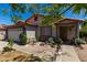 Home's front facade with partial view of 2-car garage and desert landscaped front yard featuring mature trees at 7403 W Montebello Ave, Glendale, AZ 85303