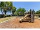 Outdoor community playground featuring a slide, a climbing wall, and mature trees at 7726 E Baseline Rd # 125, Mesa, AZ 85209