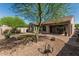 Landscaped backyard with mature trees, desert plants, decorative rock, and a covered patio area at 10412 W Cottontail Ln, Peoria, AZ 85383
