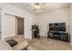 Spacious living room featuring a ceiling fan, multiple doors, and a television setup at 10412 W Cottontail Ln, Peoria, AZ 85383