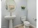 Charming powder room with pedestal sink, round mirror, and decorative floral accents at 10412 W Cottontail Ln, Peoria, AZ 85383