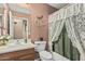 Charming bathroom features a single sink vanity, toilet, and shower/tub combo with lace curtain at 18297 W Spencer Dr, Surprise, AZ 85374