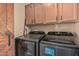 Practical laundry area with front loading machines, upper cabinets, and a rustic barn door at 18297 W Spencer Dr, Surprise, AZ 85374