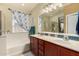 Bathroom featuring dual sinks, a large mirror, and a separate tub and shower at 18669 W Vista Norte St, Goodyear, AZ 85338