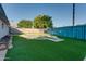 A spacious backyard with artificial turf, a pool, and a blue fence with cactus paintings offers a charming outdoor retreat at 217 E Bruce Ave, Gilbert, AZ 85234