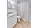 Bright bathroom featuring granite counters, white cabinets, and a tiled shower with a striped curtain at 217 E Bruce Ave, Gilbert, AZ 85234