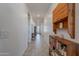 Bright hallway with tile flooring, featuring built-in wooden shelves and cabinets, leading to a front door with glass features at 32729 N Mach Ln, San Tan Valley, AZ 85143