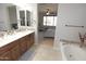 Bathroom featuring a double vanity with wood cabinets, a soaking tub, and access to the bedroom at 3581 S Arizona Pl, Chandler, AZ 85286