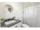 Bright bathroom featuring a round mirror, black countertop, and walk-in shower at 4238 W Krall St, Phoenix, AZ 85019