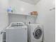 The laundry room has a white washer and dryer with a shelf stocked with essentials at 44853 W Jack Rabbit Trl, Maricopa, AZ 85139