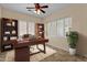 Well-lit home office with a wooden desk, ample storage, and plantation shutters at 4528 E Donato Dr, Gilbert, AZ 85298