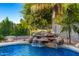Beautiful pool features a rock waterfall and lush landscaping with a clear blue sky at 5139 S Marble St, Gilbert, AZ 85298