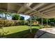 Lush backyard with green grass, mature trees, wood fence, and covered patio with seating at 743 W Ocotillo Rd, Phoenix, AZ 85013