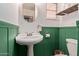 A bathroom featuring green wainscoting, white walls, a pedestal sink, mirror and a toilet at 743 W Ocotillo Rd, Phoenix, AZ 85013