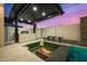 Backyard features a covered outdoor kitchen, sunken seating area with a fire pit, and a swimming pool at 8038 E Clarendon Ave, Scottsdale, AZ 85251