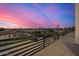 Balcony view showcasing a neighborhood street with green trees and a pool against a vibrant, colorful sunset sky at 8038 E Clarendon Ave, Scottsdale, AZ 85251