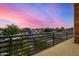 Balcony view showcasing a neighborhood street with green trees against a vibrant, colorful sunset sky at 8038 E Clarendon Ave, Scottsdale, AZ 85251
