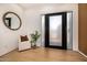 Inviting foyer with a stylish round mirror, cozy chair, and modern wood-slatted accent wall at 8038 E Clarendon Ave, Scottsdale, AZ 85251
