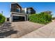 Modern two-story home with a black garage and lush green landscaping at 8038 E Clarendon Ave, Scottsdale, AZ 85251
