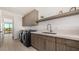 Bright laundry room with modern washer/dryer, ample cabinet space, a sink, and a view to the house's entrance at 8038 E Clarendon Ave, Scottsdale, AZ 85251