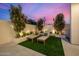 Outdoor patio features two lounge chairs, green artificial grass, and decorative shrubbery with accent lighting at 8038 E Clarendon Ave, Scottsdale, AZ 85251